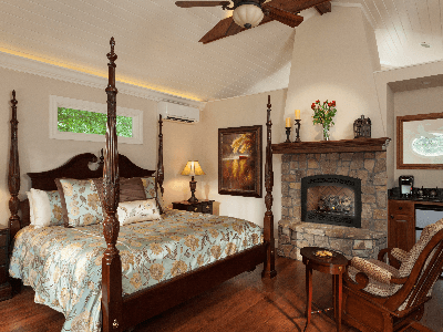 Carriage House Suite bedroom and sitting area bedroom with four-poster king-size bed and sitting area with glider chairs and fireplace