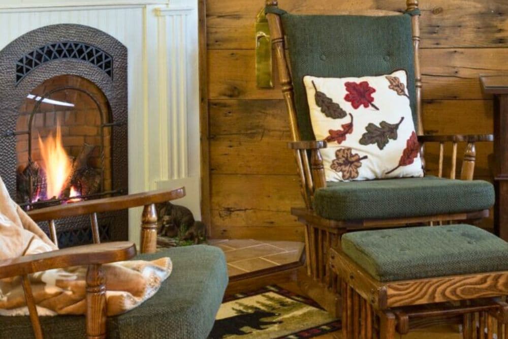 Cozy living room featuring a rocking chair with a seasonal pillow and a warm fireplace.