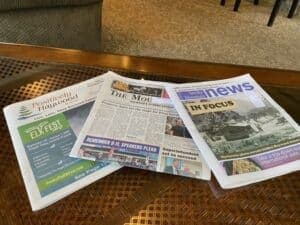 Three newspapers spread out on a table.