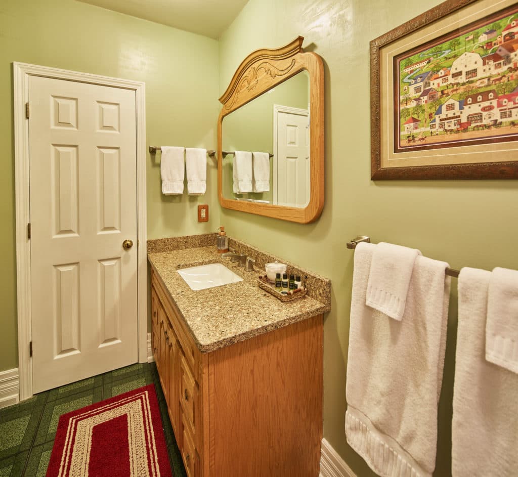 A cozy bathroom featuring a granite countertop, large mirror, and two neatly hung towels.