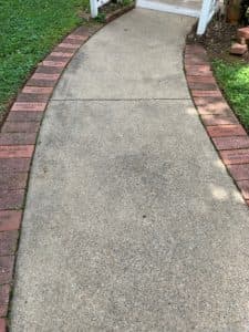 A curved concrete walkway bordered by red bricks.