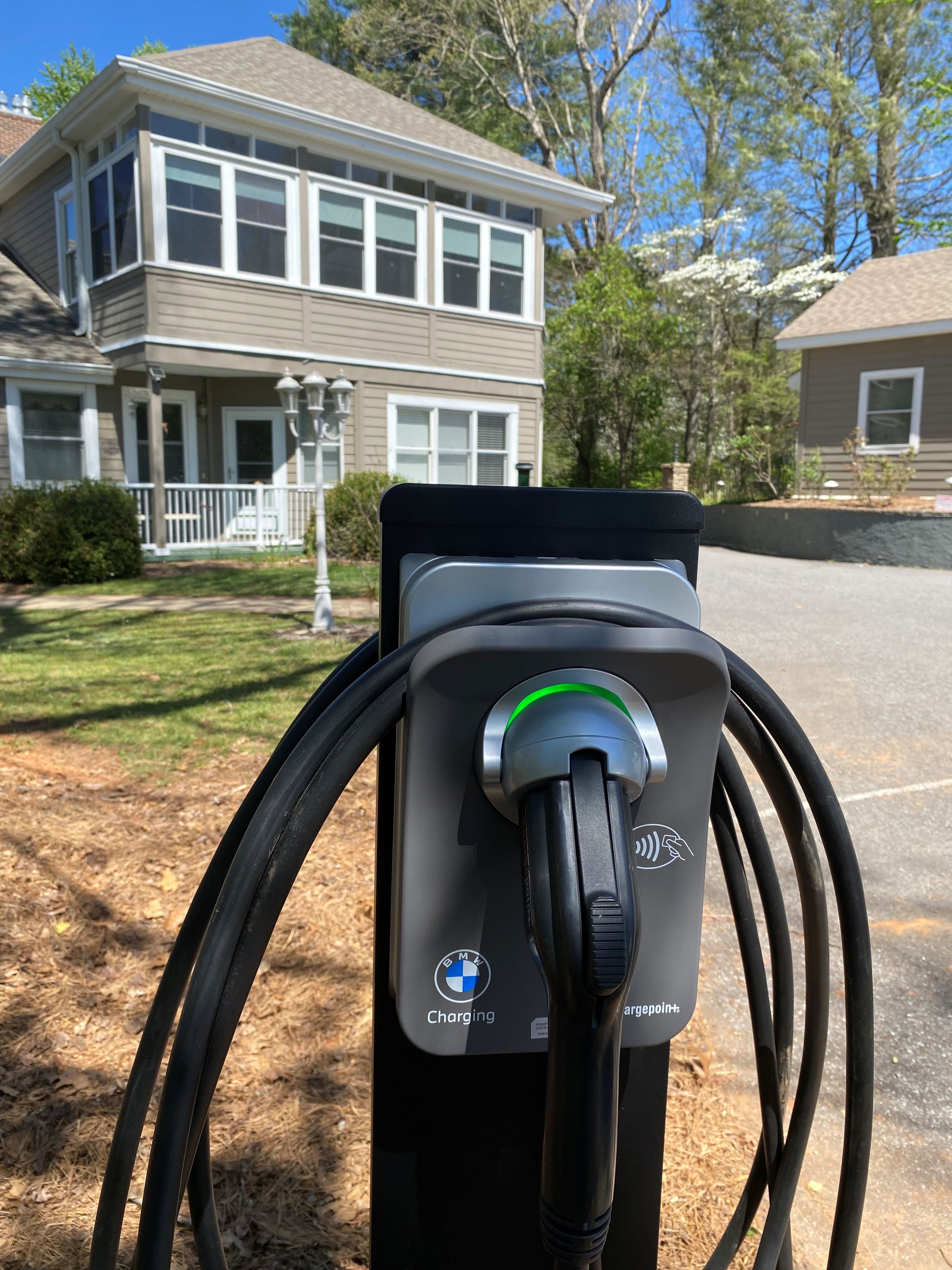 An electric vehicle charging station with cables in front of a house.