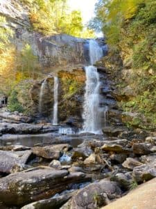 A picturesque waterfall cascading over rocky terrain surrounded by vibrant autumn foliage.