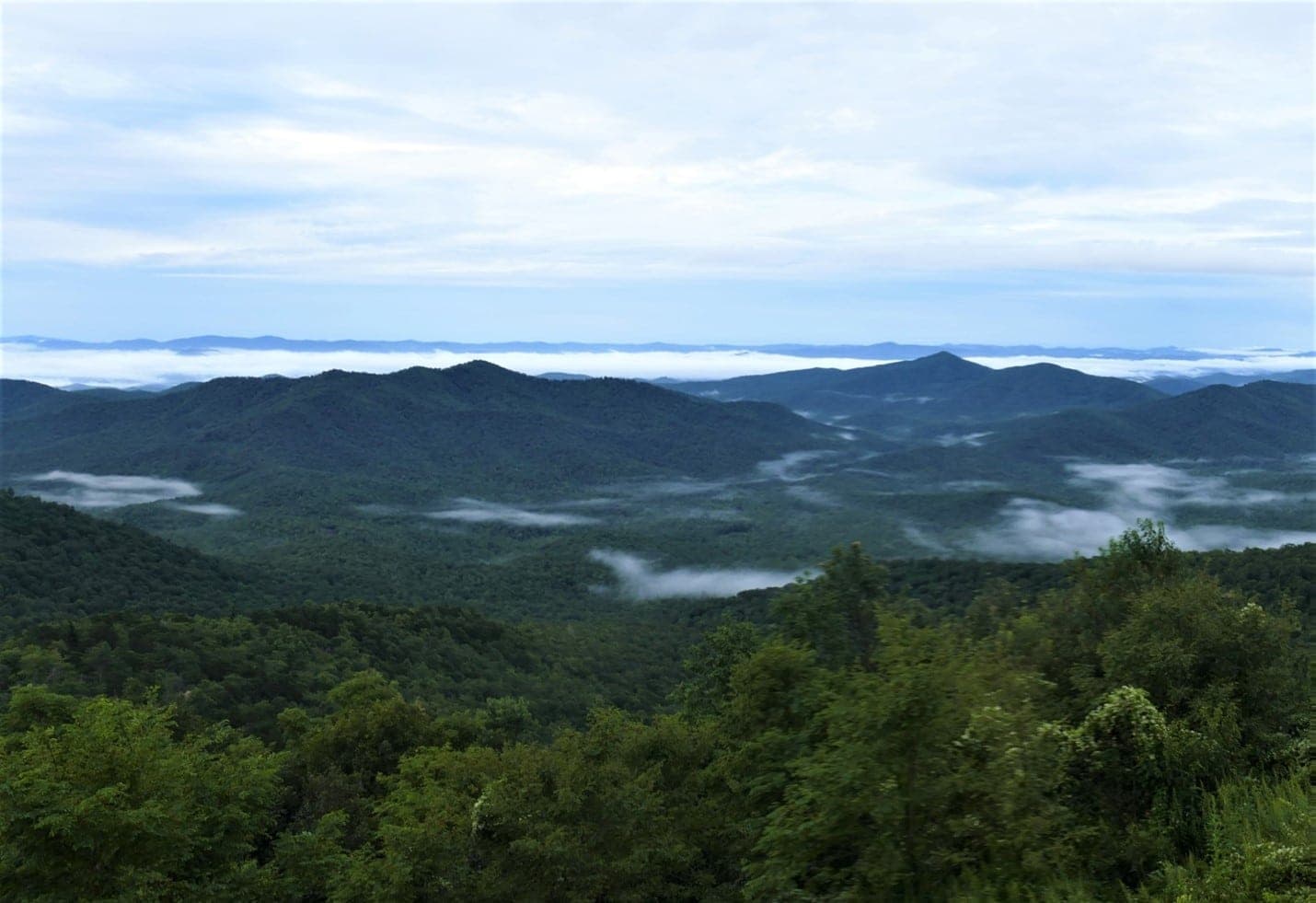 A misty view of rolling green mountains under a cloudy sky.
