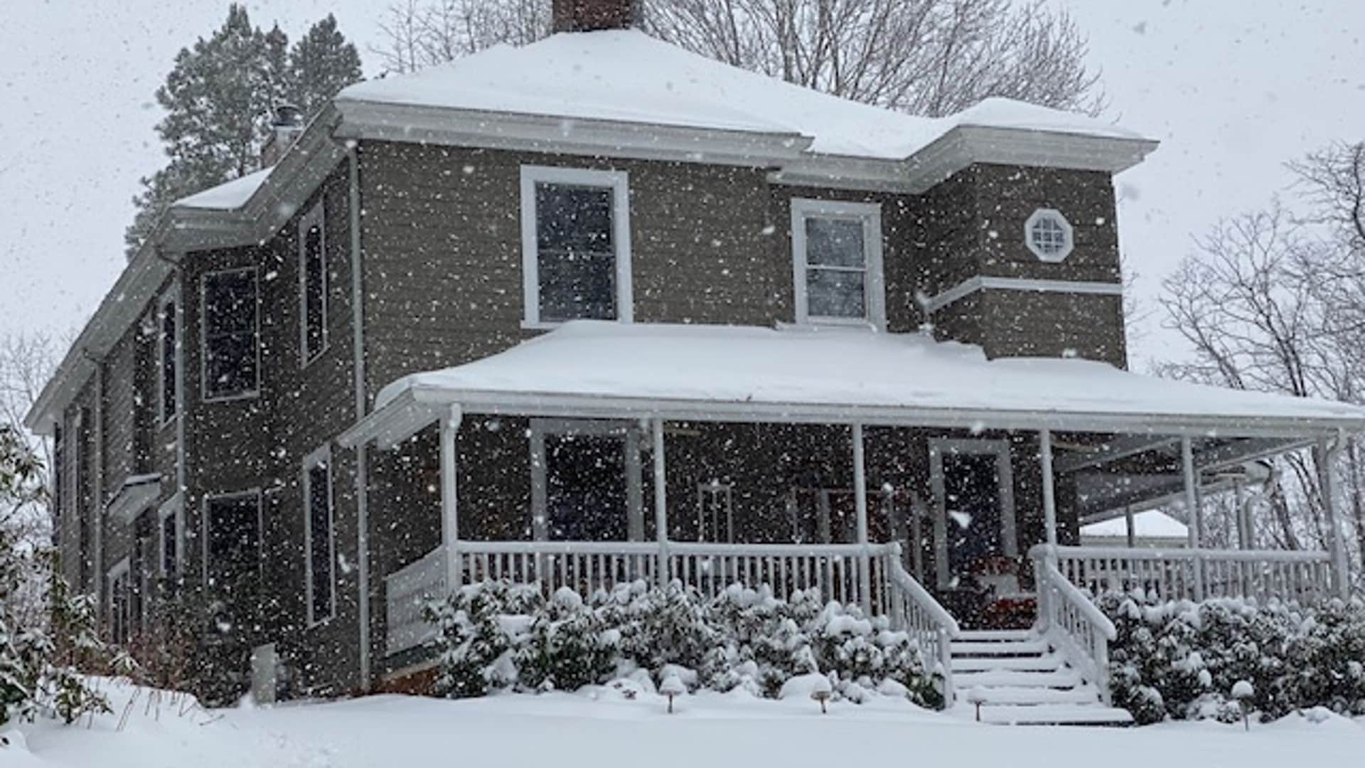 A snow-covered house surrounded by trees in a winter snowfall. A snow-covered house surrounded by trees in a winter snowfall.