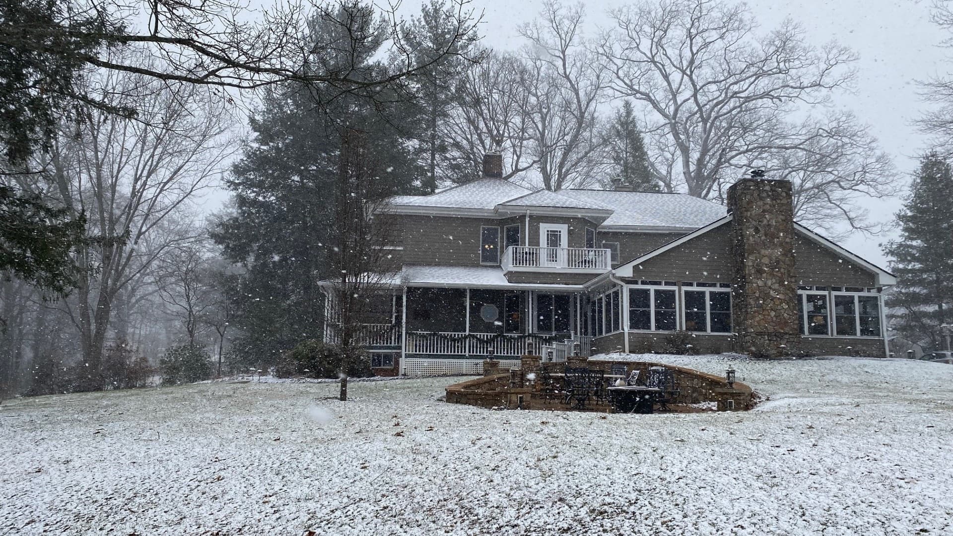 A snow-covered house surrounded by trees during a snowfall. A snow-covered house surrounded by trees during a snowfall.