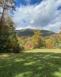 A scenic view of a mountain surrounded by autumn foliage under a partly cloudy sky.
