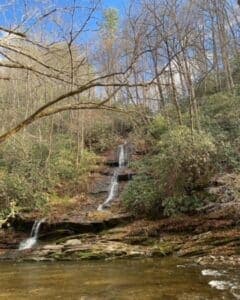 A serene waterfall cascading down a rocky slope, surrounded by trees and greenery.
