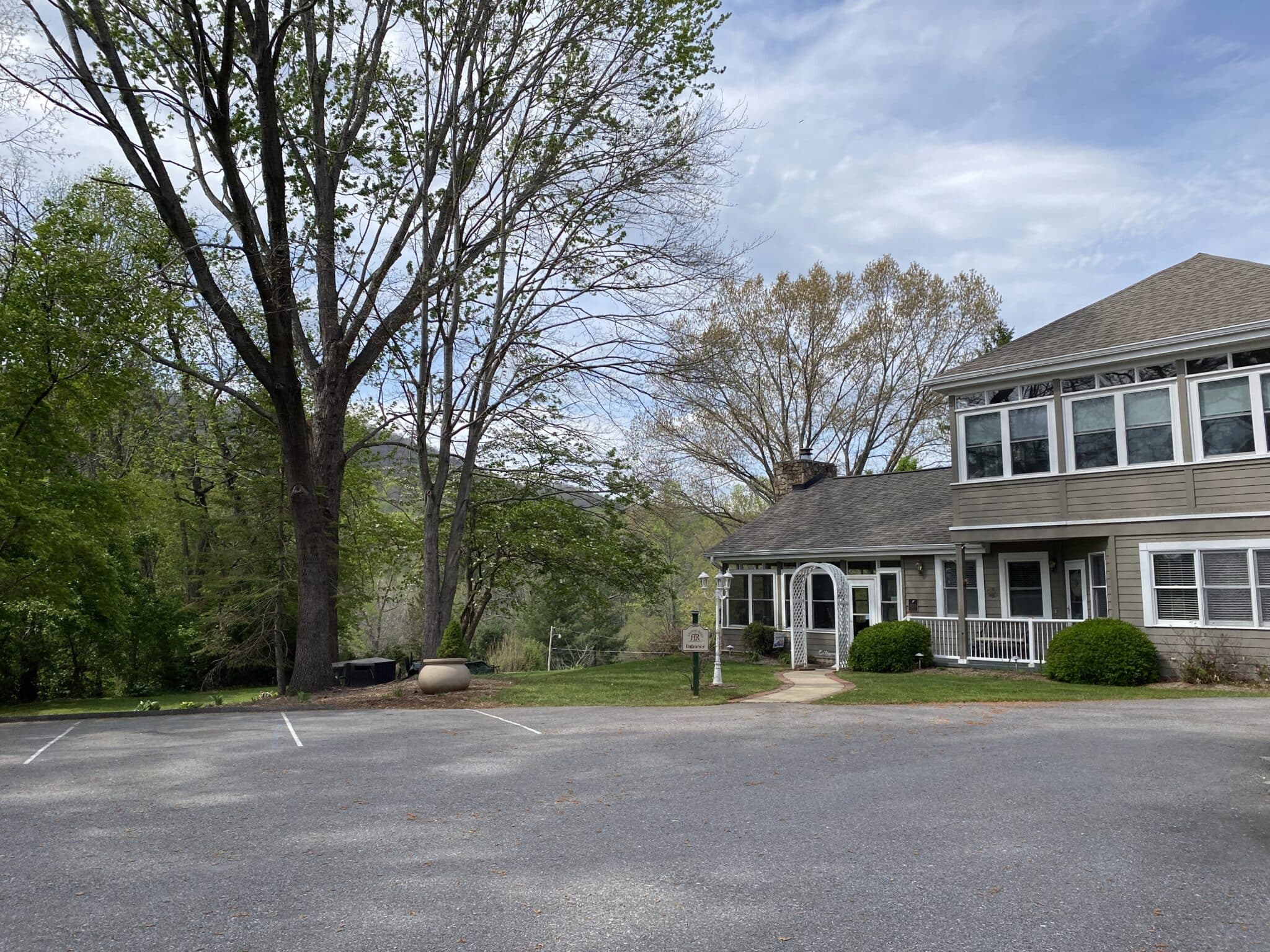 A parking area next to a two-story building surrounded by trees.