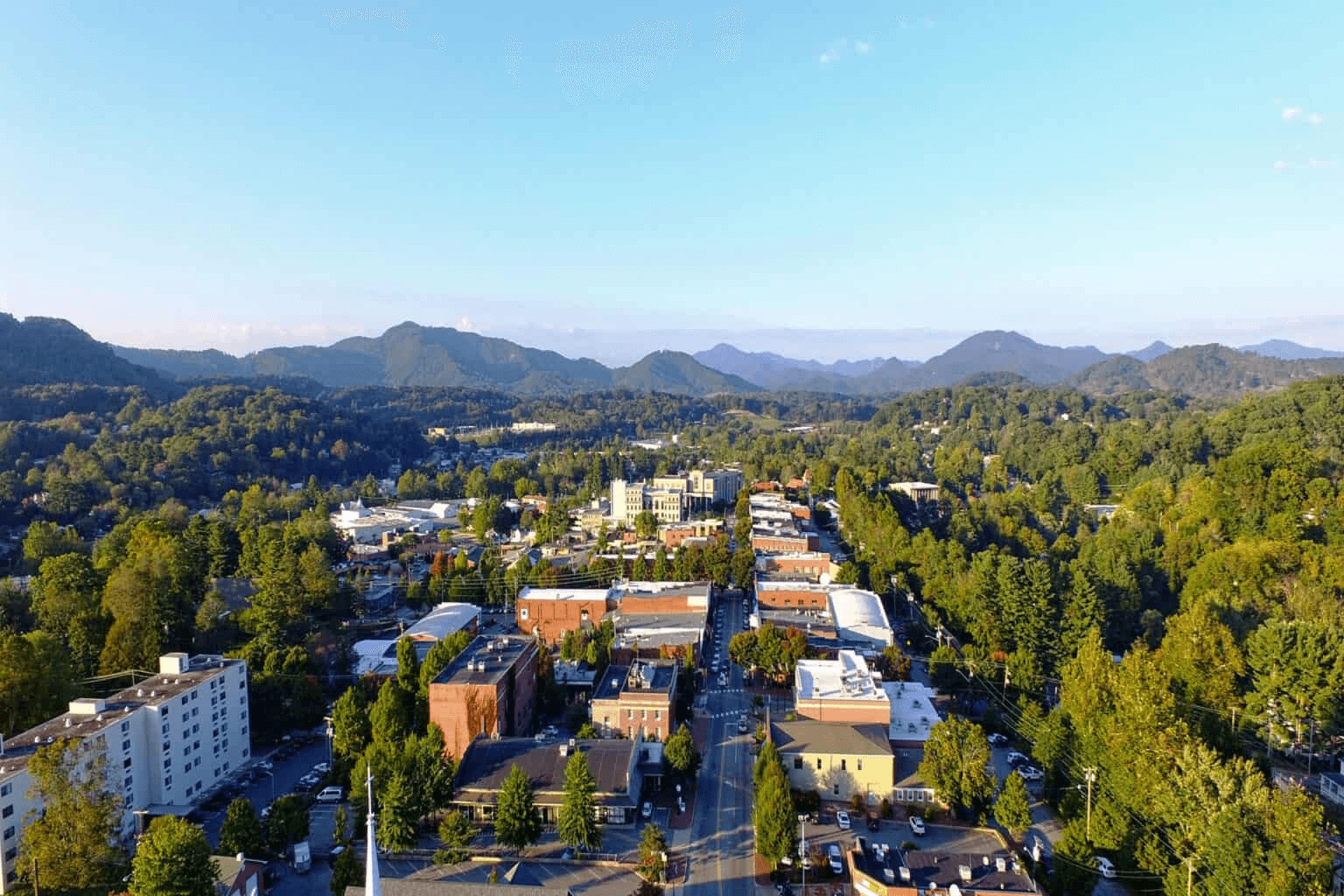 Aerial view of a small town surrounded by lush green mountains under a clear blue sky. Aerial view of a small town surrounded by lush green mountains under a clear blue sky.