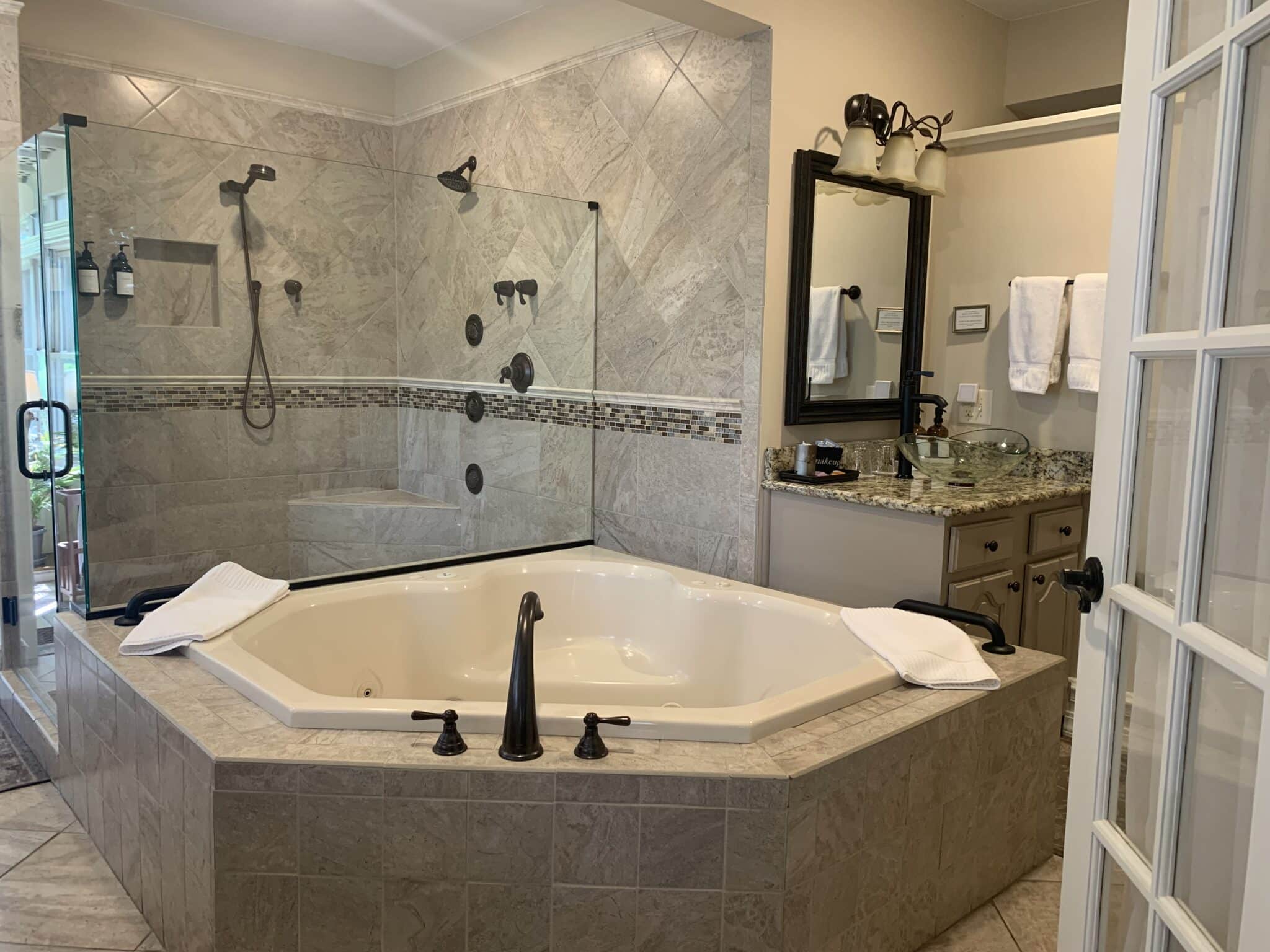 A luxurious bathroom featuring an octagonal jetted tub, glass shower, and granite countertops. A luxurious bathroom featuring an octagonal jetted tub, glass shower, and granite countertops.