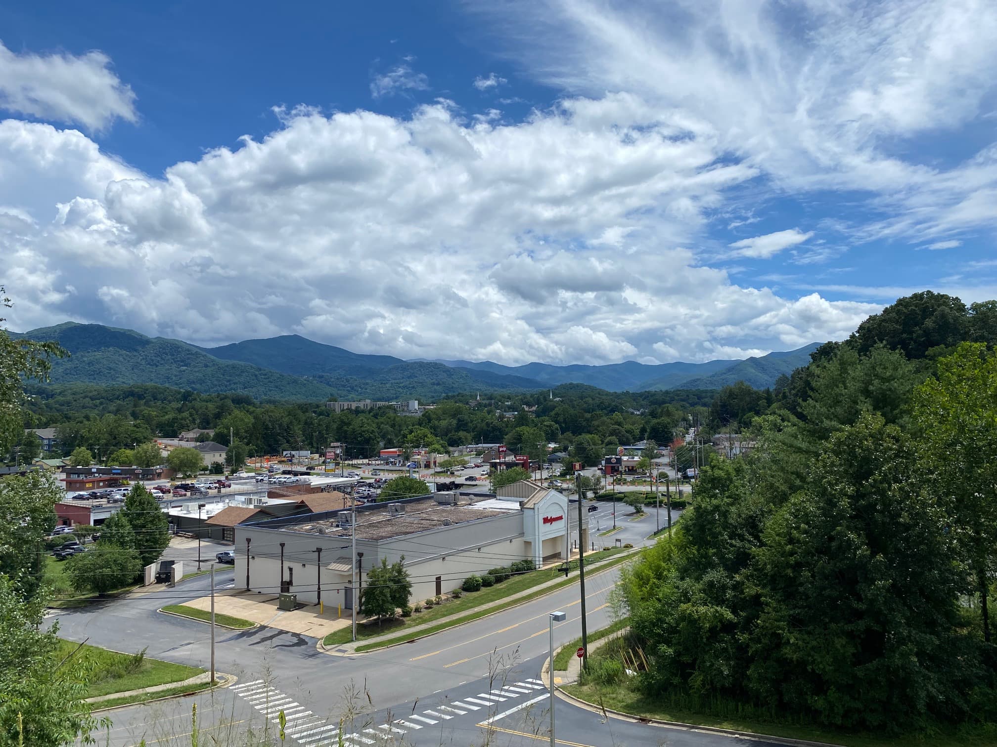 A scenic view of a town with mountains in the background and a mix of businesses in the foreground under a partly cloudy sky.