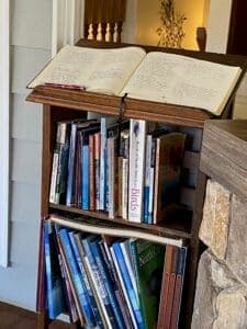 A wooden bookshelf containing various books, with an open book on top.