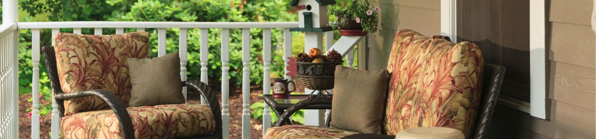 Cozy outdoor seating area with patterned cushions and greenery in the background.