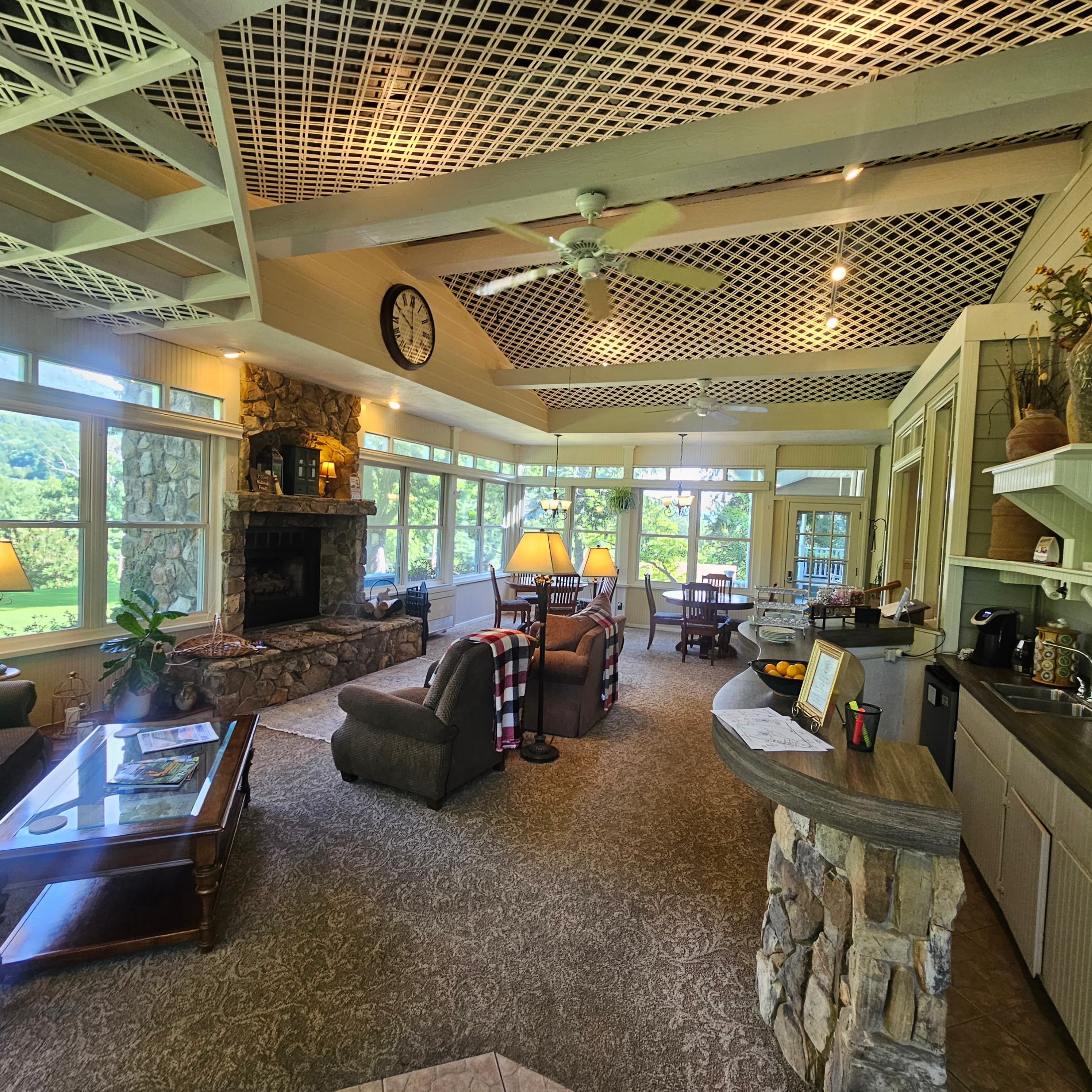 A bright, airy sunroom features stone walls, a cozy fireplace, and comfortable seating.