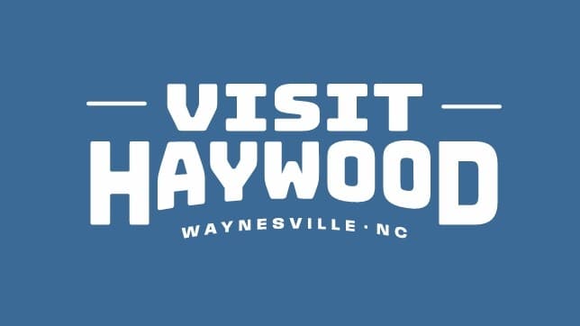 Text logo that says "Visit Haywood" with "Waynesville, NC" beneath it, all on a blue background.