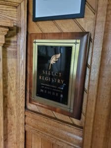 A plaque displaying "Select Registry" mounted on a wooden wall.
