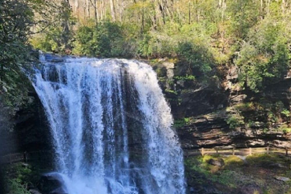 A picturesque waterfall cascading over rocky cliffs, surrounded by lush greenery.