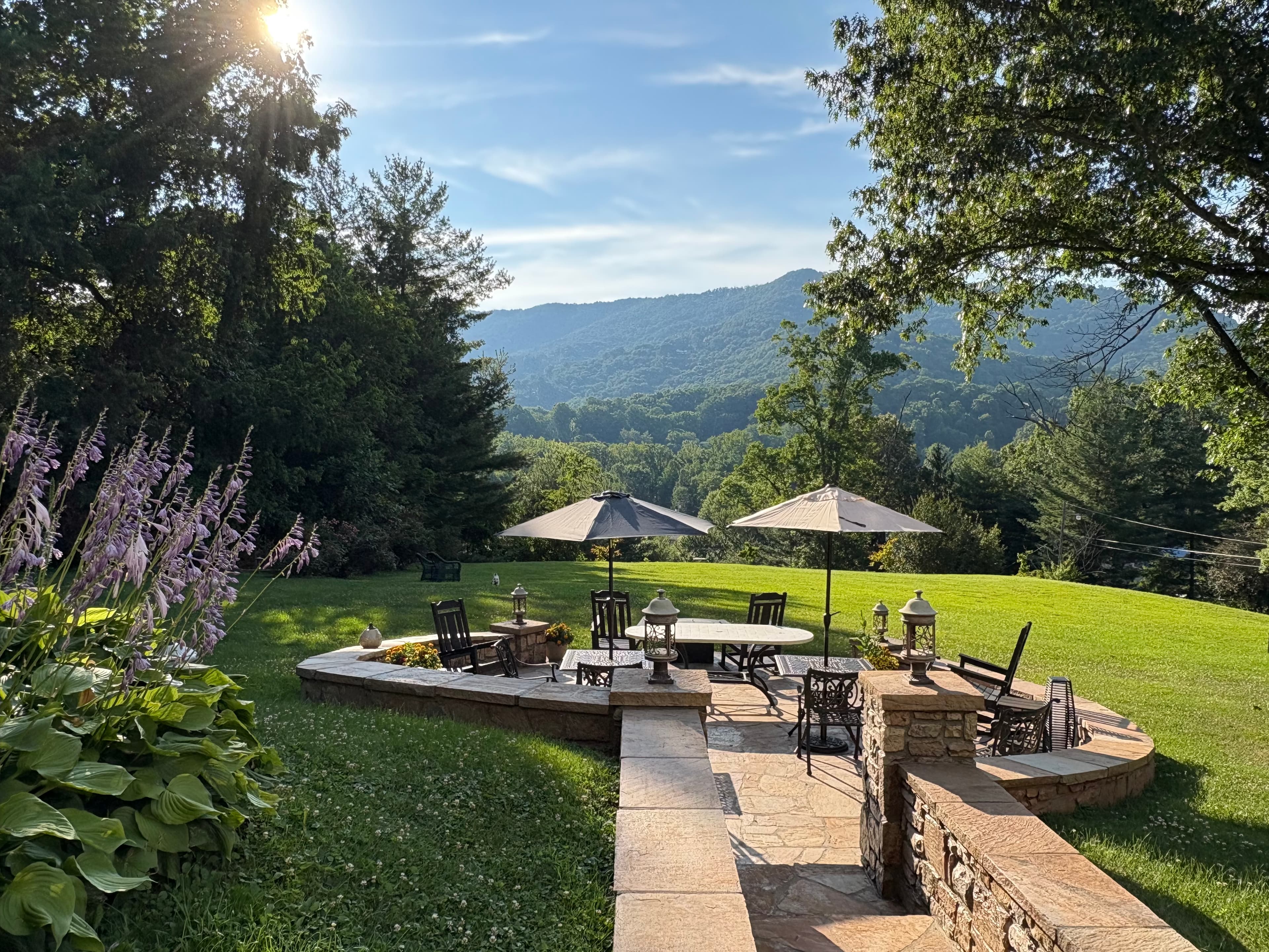 Stunning outdoor patio surrounded by green lawn, trees and mountains in the distance Stunning outdoor patio surrounded by green lawn, trees and mountains in the distance