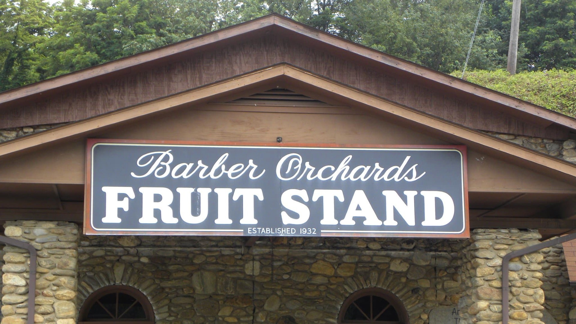 A brown stone building with a large stand for a fruit orchard