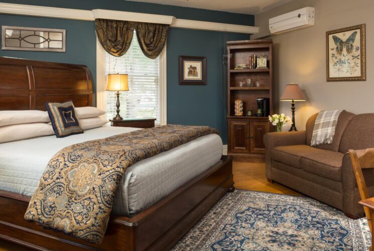 Elegant bedroom in blue and taupe hues with king bed, couch, and large window