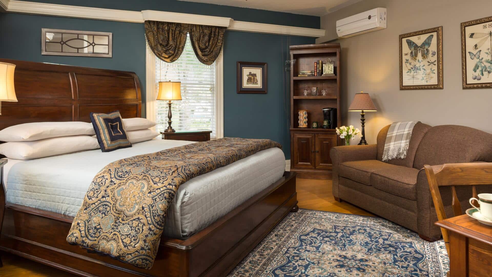 Elegant bedroom in blue and taupe hues with king bed, couch, and large window
