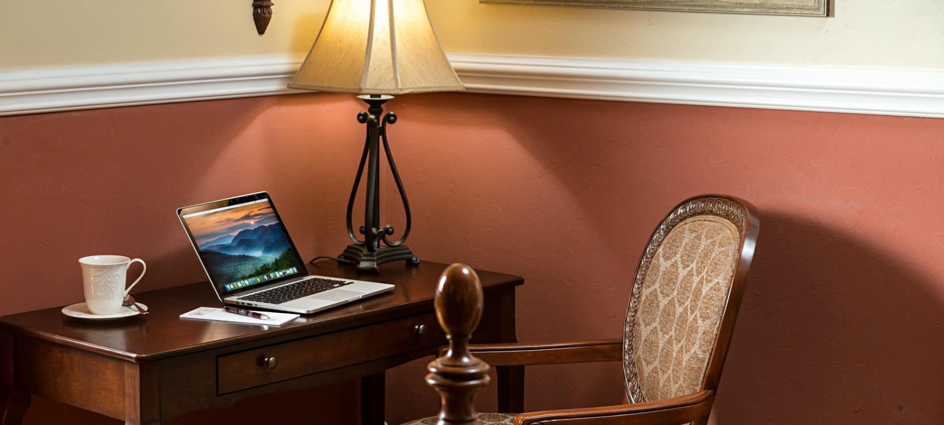 Terracotta and cream room, small wood desk and chair in the corner with laptop and white cup and saucer