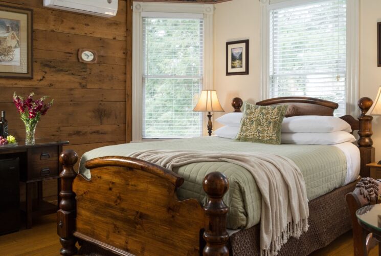 Cozy bedroom with wood tones, large windows and hutch with flowers and fine and fruit