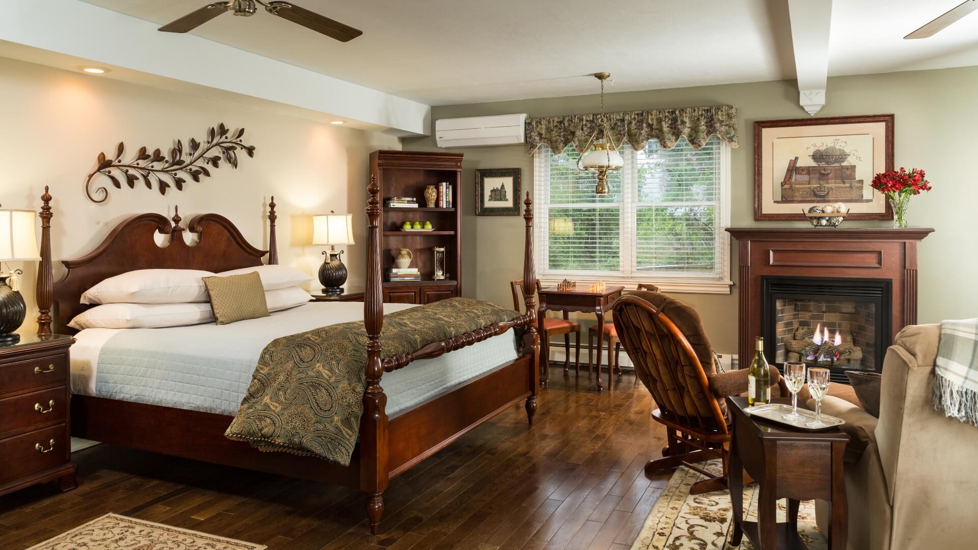 Spacious bedroom with king four poster bed, sitting table an two chairs in front of a fireplace