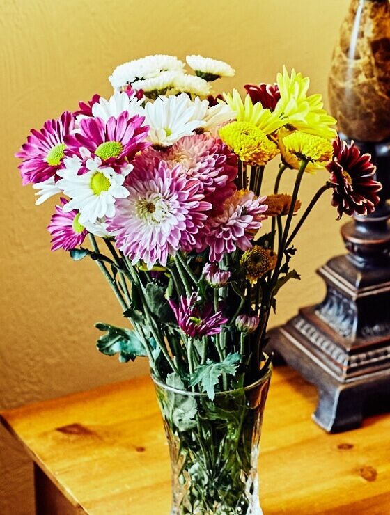 Vase of pink, yellow and white flowers on a bedside table