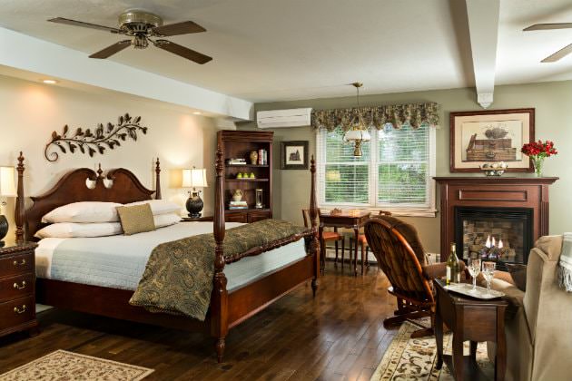 Elegant and spacious room with cream and sage walls, wood floors, four poster bed, fireplace, sitting area, and double window