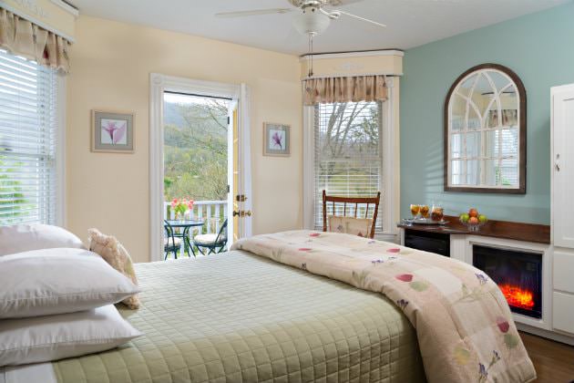 Serene beige room, light blue accent wall, gas fireplace, natural light, French door to patio with beautiful wooded views