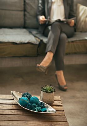 Woman wearing gray suit sitting on a sofa reading a magazine