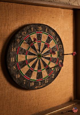 Black, white, red, and green dartboard with four red darts