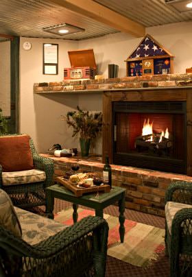 Cozy room with brick hearth and fireplace and green wicker furniture with green and white cushions