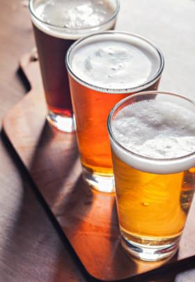 Three glasses of beer, gold, orange, and amber, with white froth