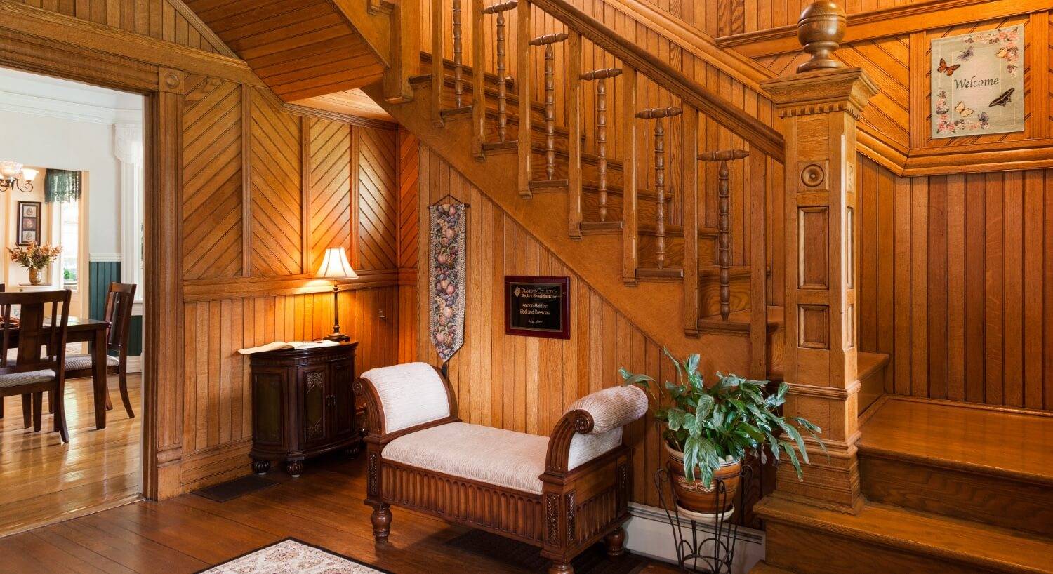 Front foyer of a home showing detailed wood paneled walls and staircase going upstairs