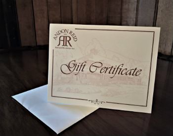 White card propped up on a table with Andon Reid Gift Certificate in red scrolly lettering